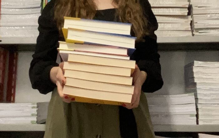 Libraia con pila di libri